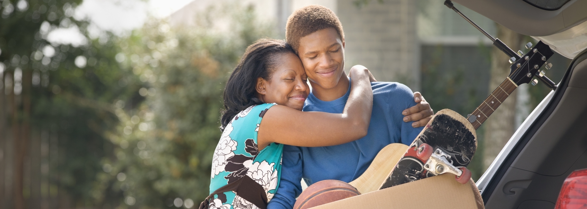 Mother hugging teenage son as he packs for college